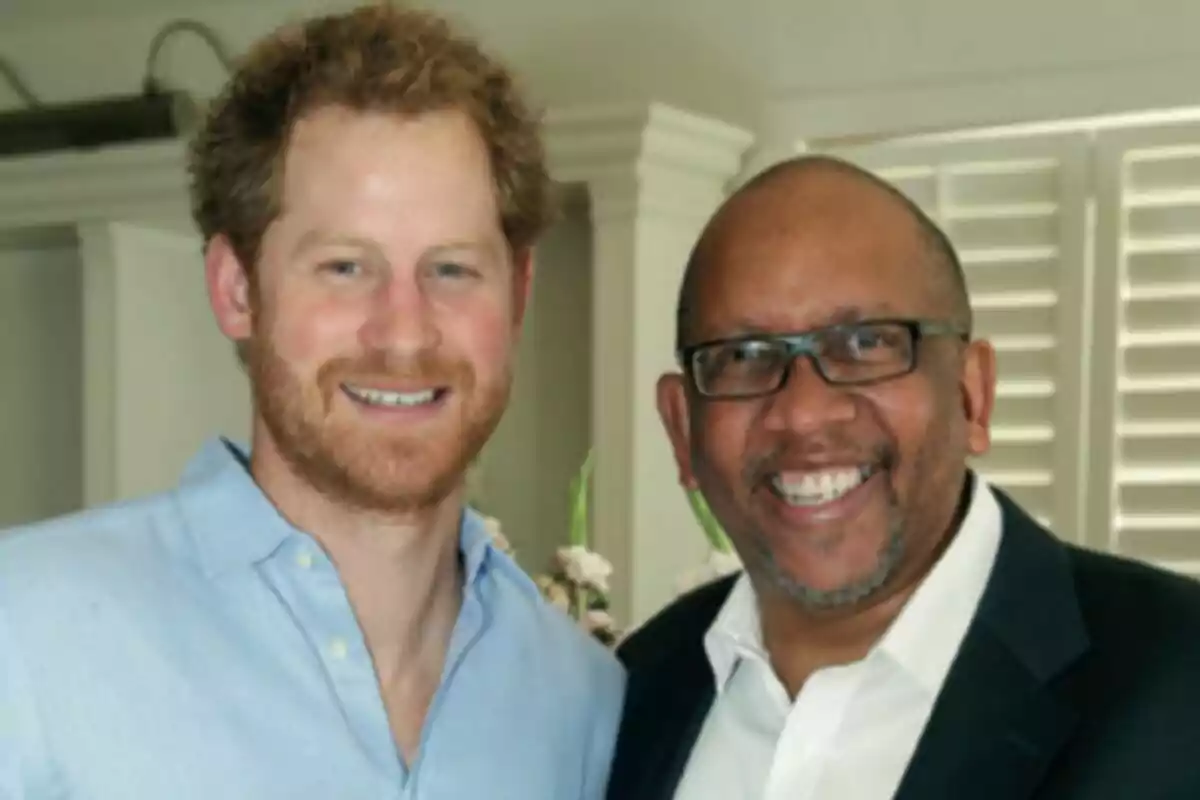 Two men smile together in a brightly lit indoor setting.