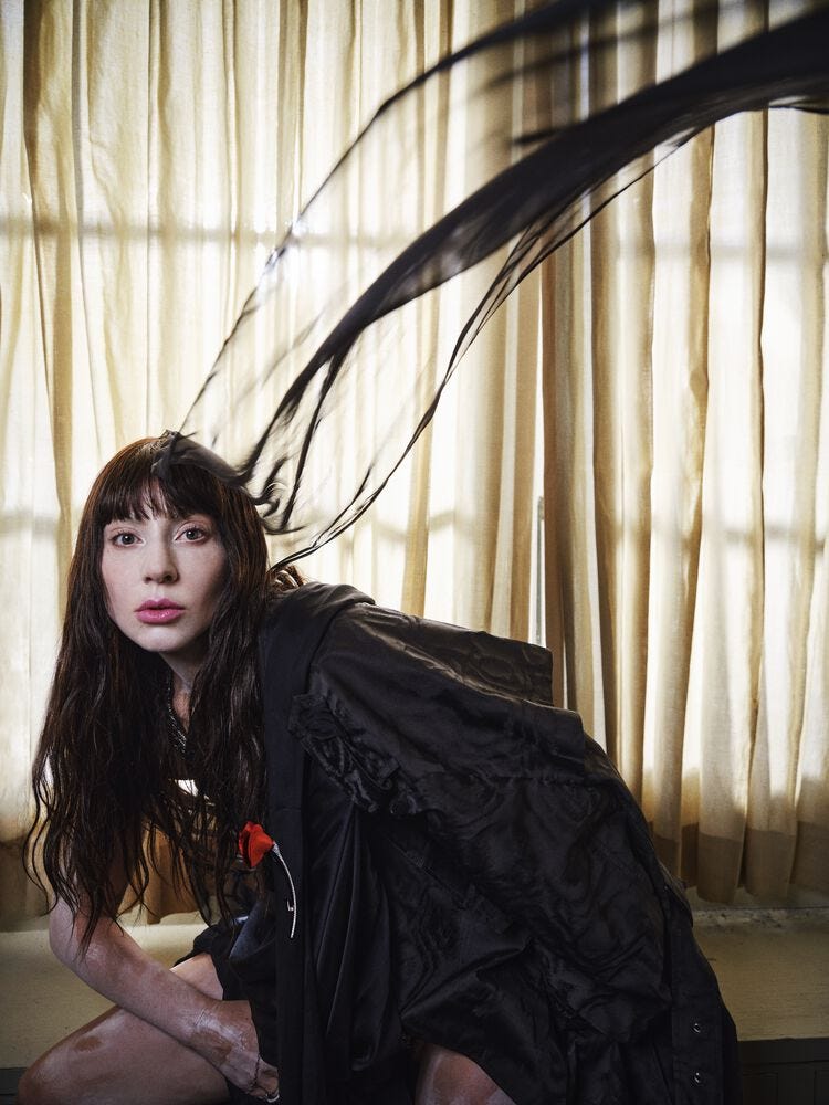 a figure in a dramatic pose draped in black fabric