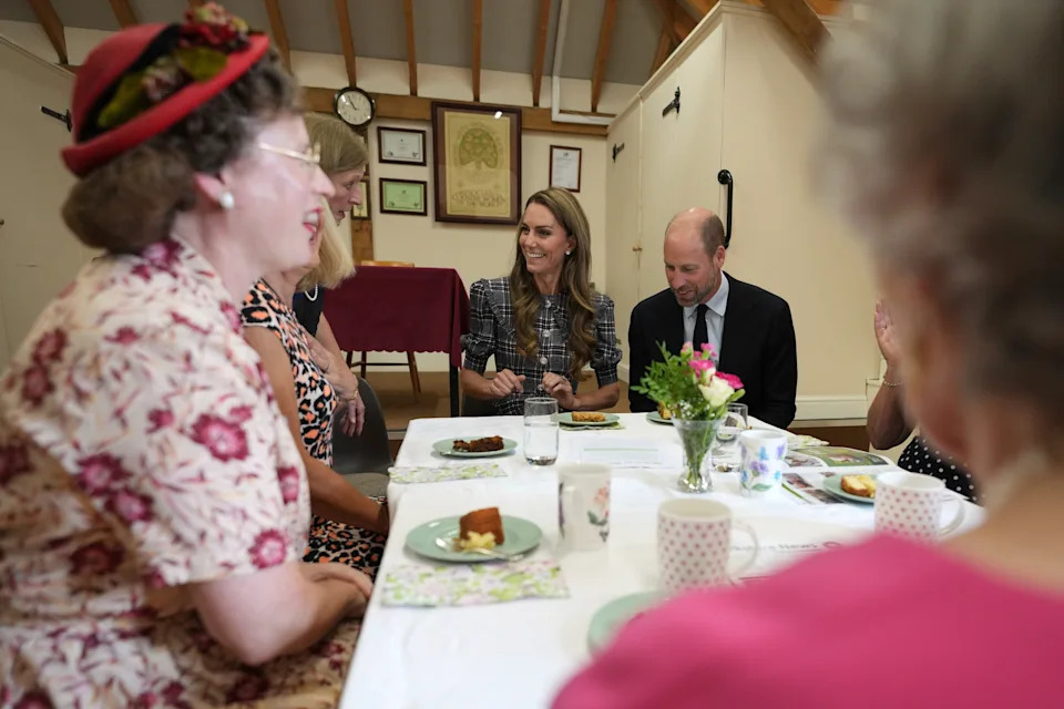 Prince William and Princess Kate sitting at a table of women eating cake