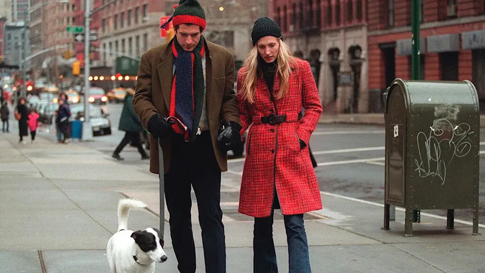 JFK Jr. and Carolyn Bessette-Kennedy looking down as they walk their dog outside.