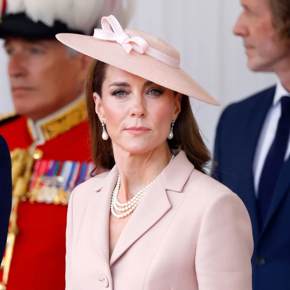  Prince William wears a suit and Kate Middleton wears a pale pink suit and matching hat. 