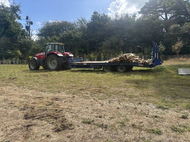 Red tractor transporting wood and other materials across the grounds of the Lodge
