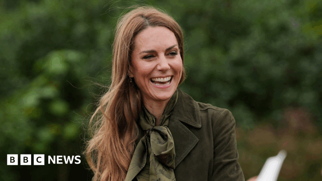 The Princess of Wales wearing a green silk scarf and a green jacket. She is laughing with a big smile on her face.