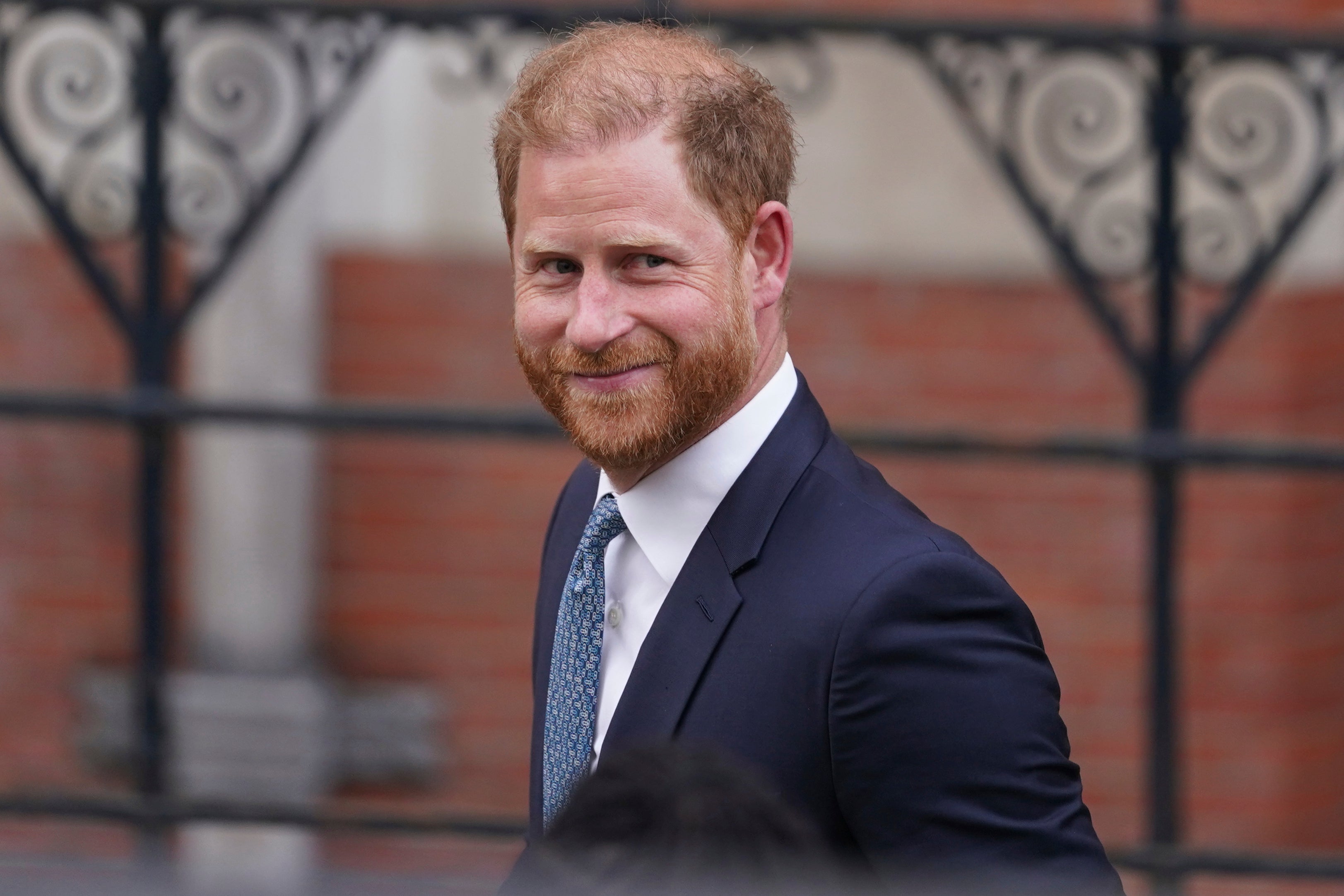 Prince Harry smiles towards the media as he leaves the Royal Courts of Justice in London