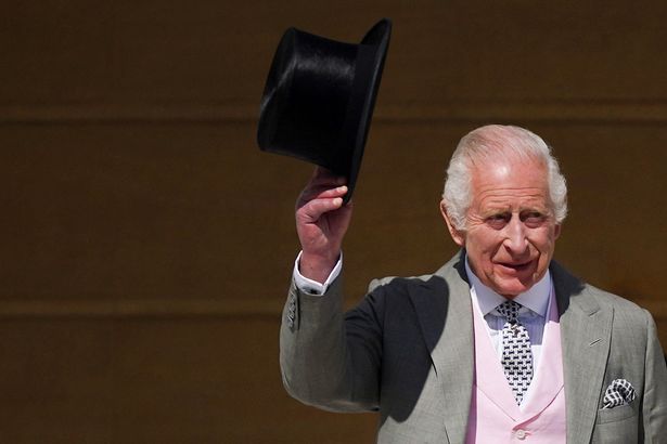 King charles holding hat outside buckingham palace in 2024