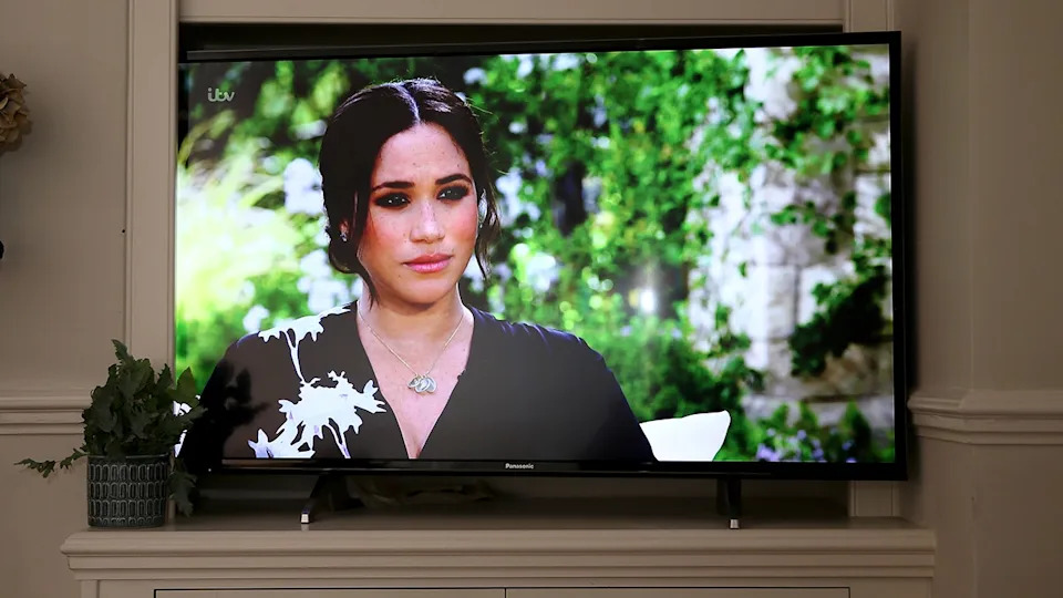 Meghan Markle in a black and white floral dress speaking from a TV screen.