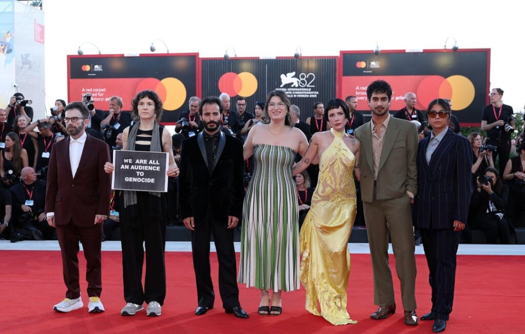 Charlie Kaufman, Eva H.D., Josef Akiki, Emily McCann Lesser, Halsey, Avan Jogia and Isabelle Deluce held up a sign saying: “We are all an audience to genocide” at ‘The Smashing Machine’ premiere during the 82nd Venice Film Festival. (September 1, 2025) Charlie Kaufman, Eva H.D., Josef Akiki, Emily McCann Lesser, Halsey, Avan Jogia and Isabelle Deluce held up a sign saying: "We are all an audience to genocide" at 'The Smashing Machine' premiere during the 82nd Venice Film Festival. (September 1, 2025)