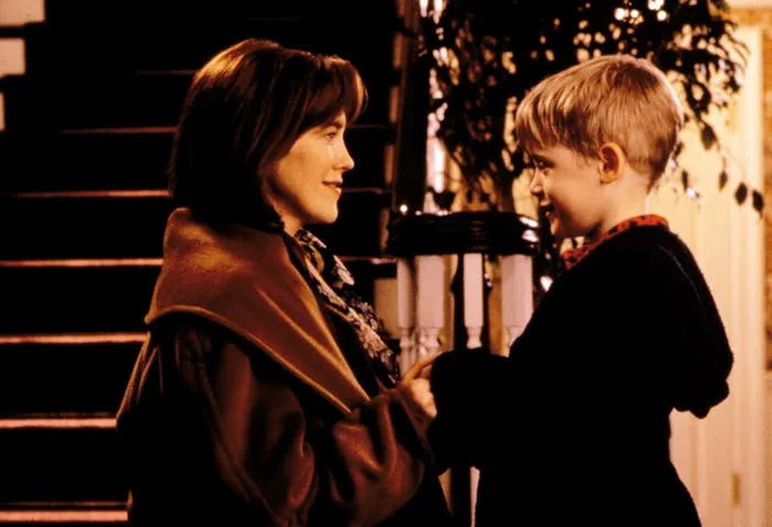 A woman and a young boy smile at each other in a warmly lit setting, suggesting a heartfelt moment