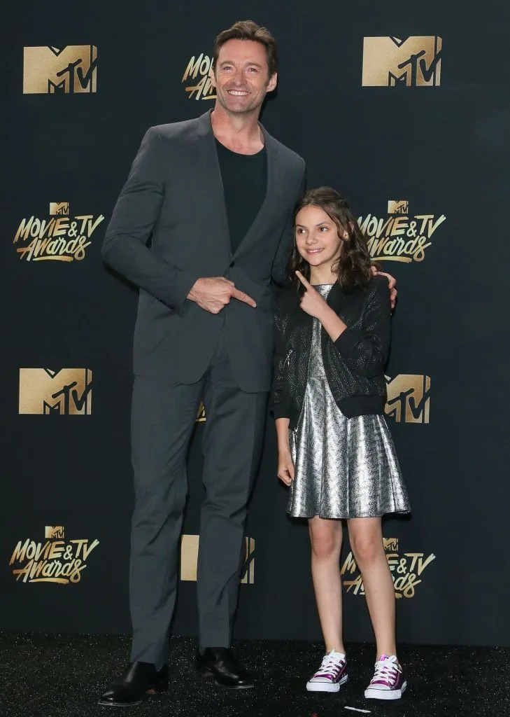 Man in suit and girl in silver dress pose playfully at MTV Movie & TV Awards