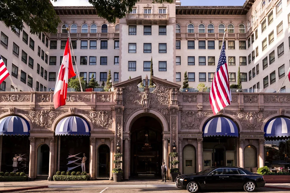 Historic hotel entrance with flags and a luxury car.
