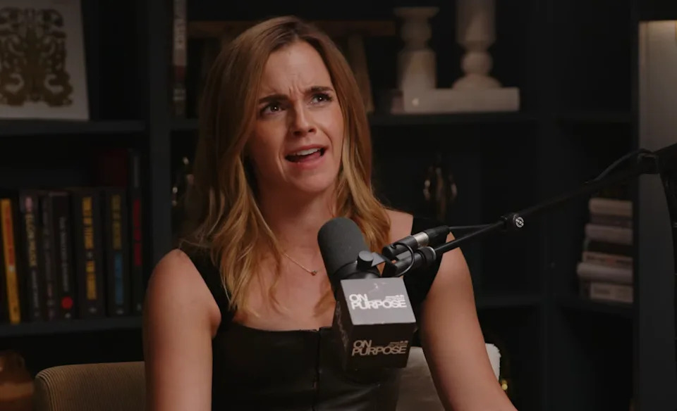Person speaking into a microphone during a podcast recording in a library setting