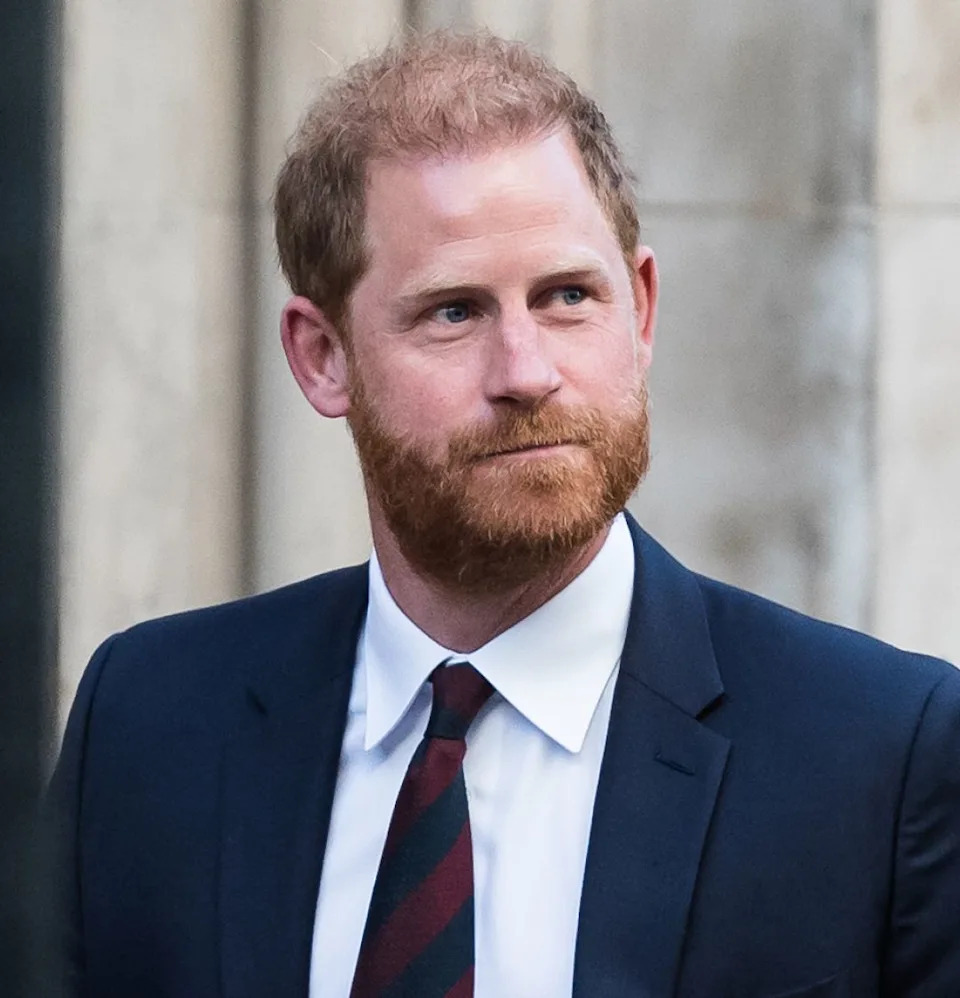  Prince Harry wearing a blue suit and red and blue striped tie . 