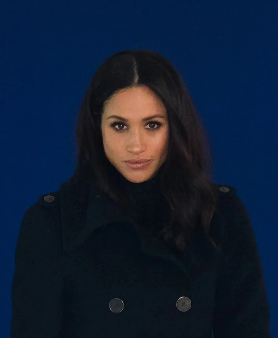 Meghan Markle looking serious wearing black.