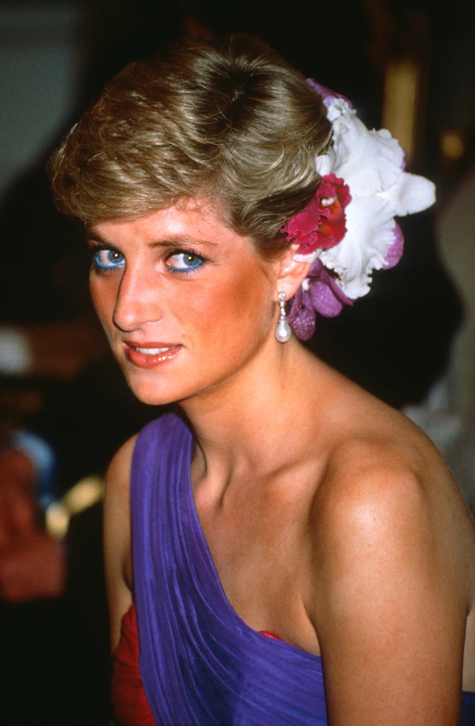 Princess Diana wearing flowers in her hair and a red and purple dress 