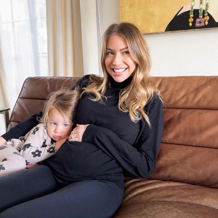 Reality TV star sitting on a brown couch with a child, expressing strong feelings towards Meghan Markle.