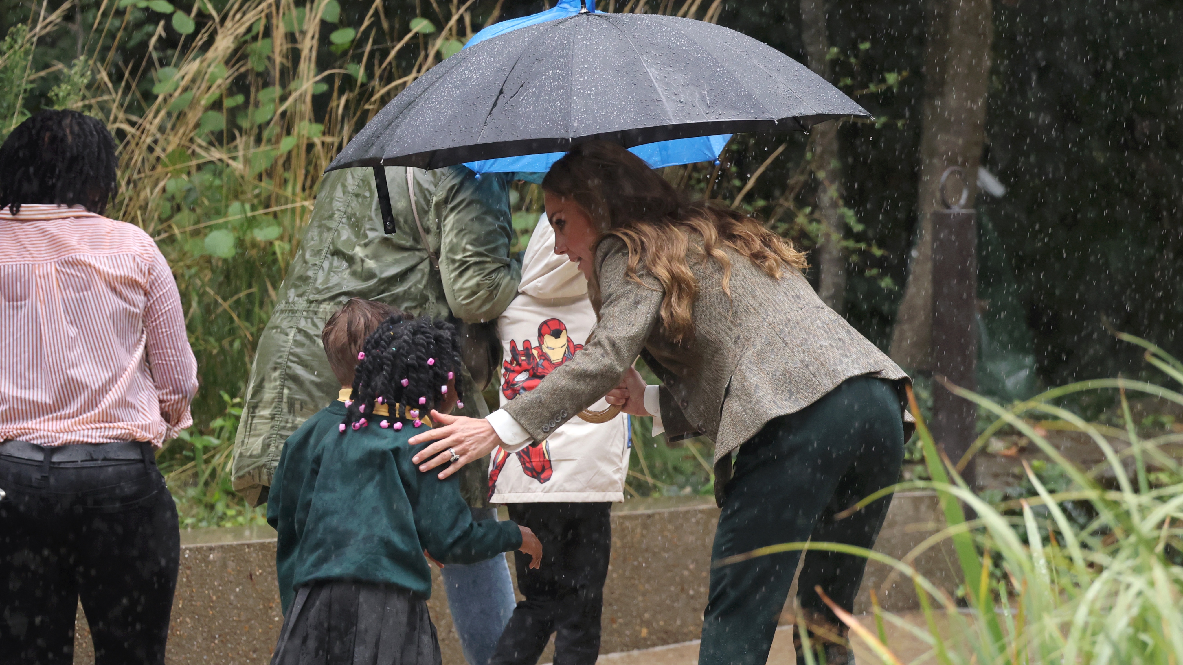 Catherine, Princess of Wales helps a child to get under her umbrella during her visit to the Natural History Museum's newly renovated gardens on September 04, 2025