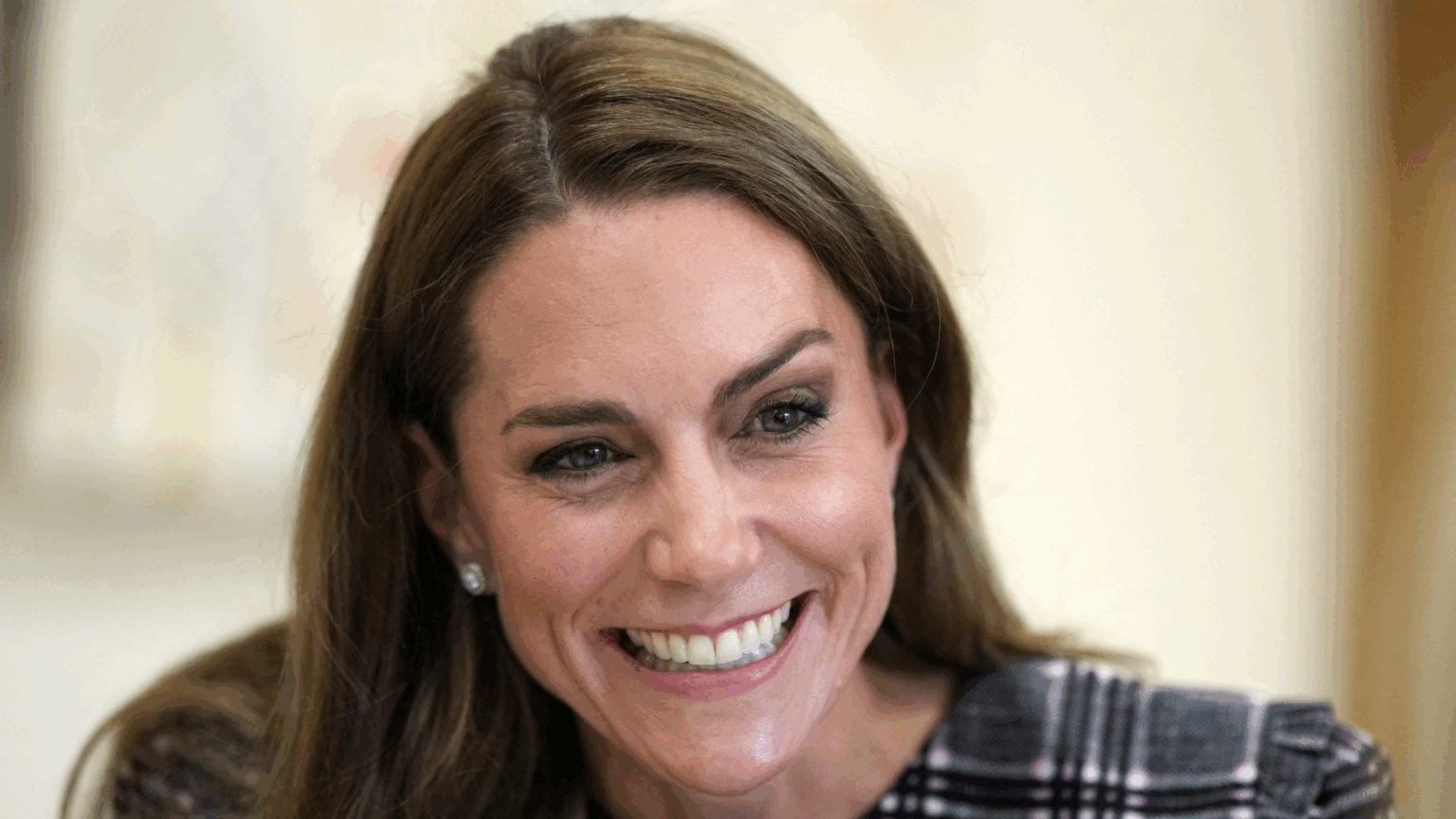 Kate Middleton smiling in a plaid dress