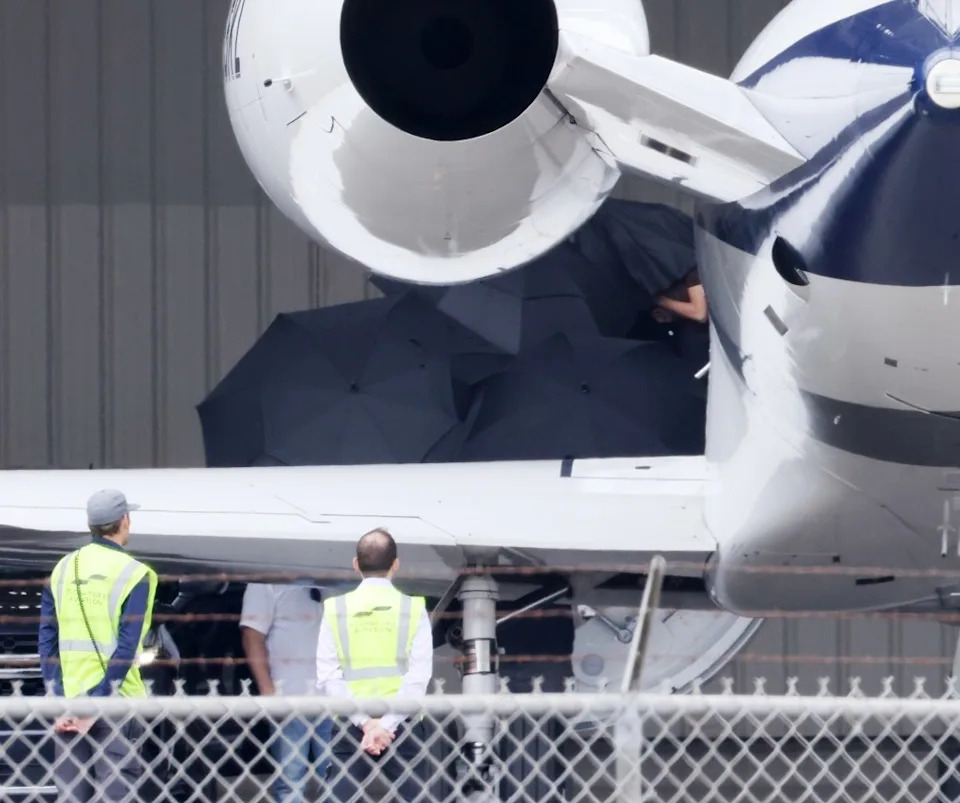 A group rushed out to meet her with the black umbrellas as she descended the aircraft’s steps. B-TEAM / BACKGRID