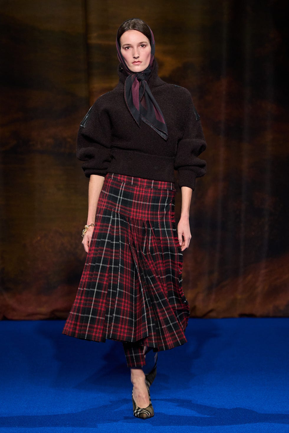 a model showcases a fashion ensemble featuring a black sweater and a plaid skirt