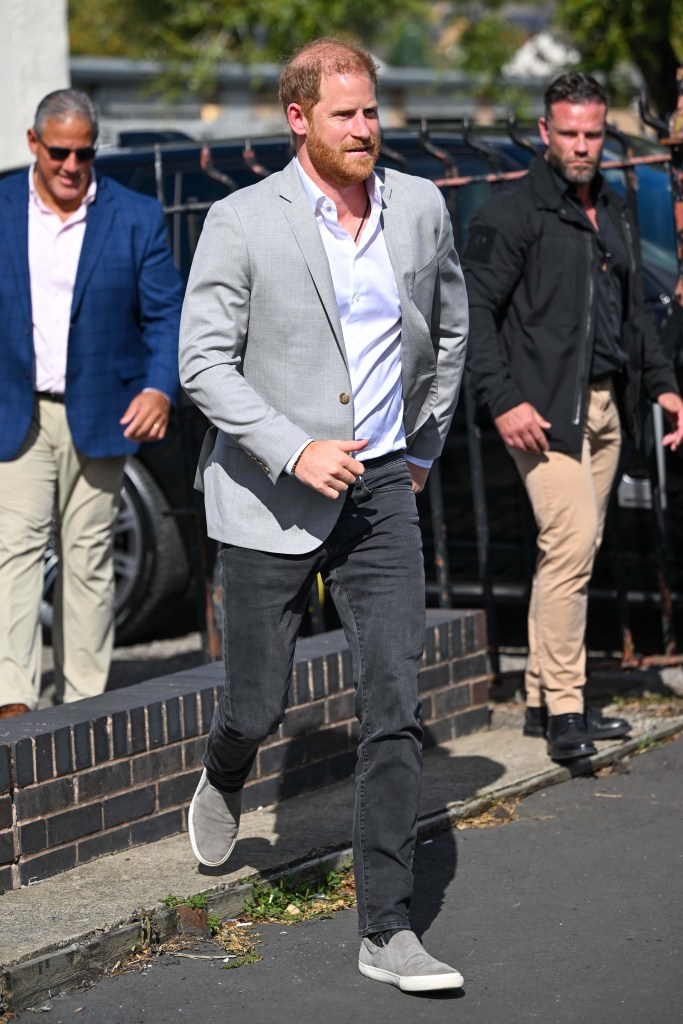 Prince Harry wears a grey suit jacket and dark trousers