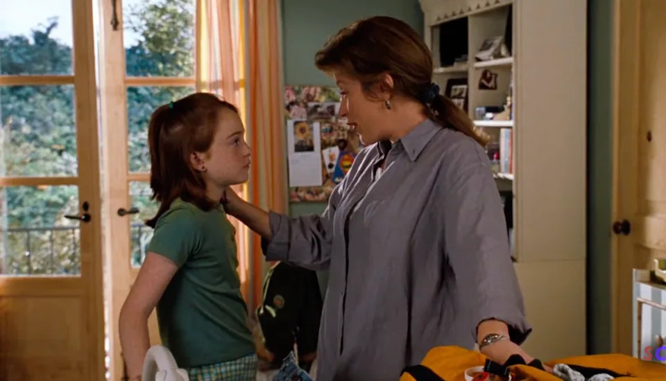 A woman and a young girl share a serious conversation in a cozy, lived-in kitchen