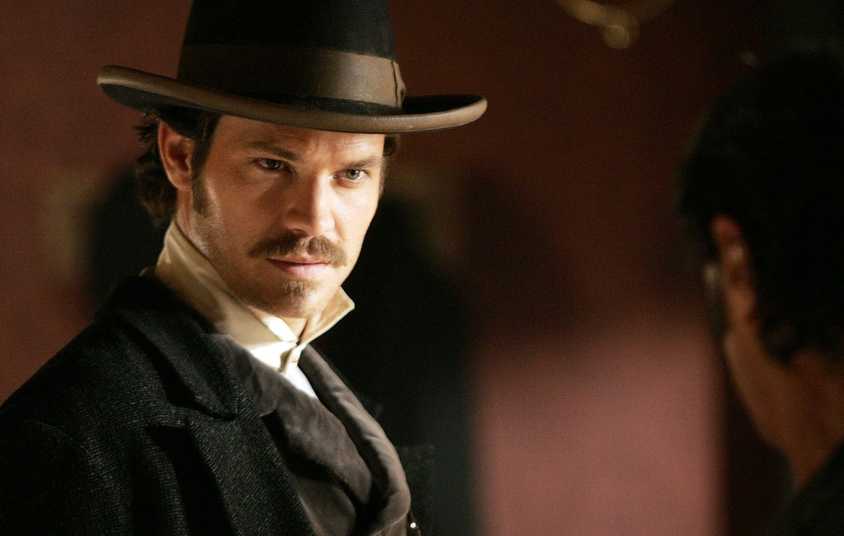 Timothy Olyphant as Seth Bullock in Deadwood, wearing a hat and looking menacingly at someone.
