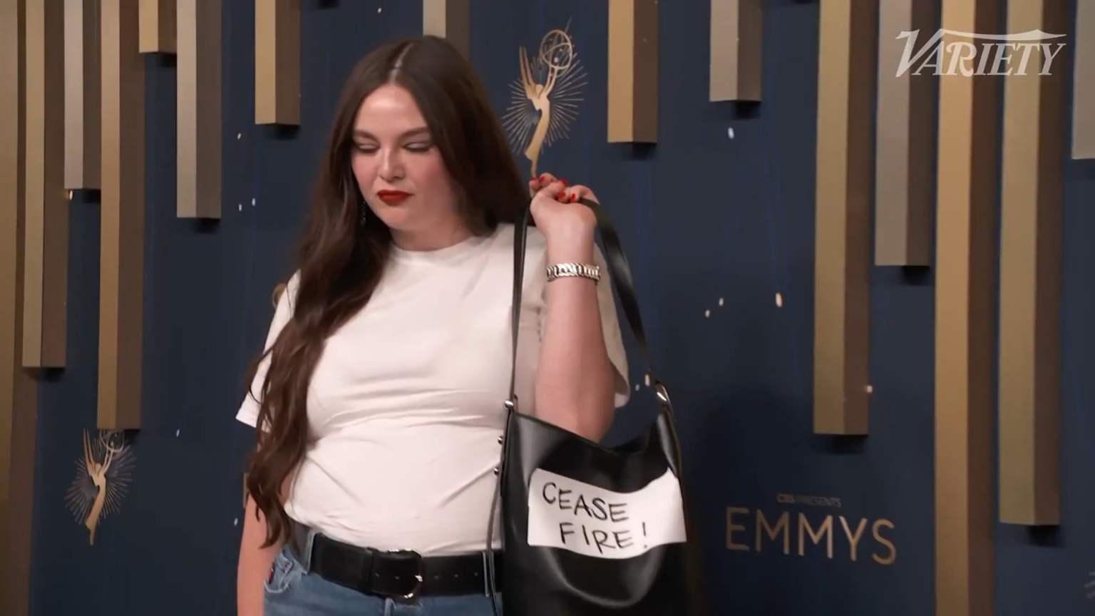 Megan Stalter showed up the 77th Primetime Emmys in jeans, a t-shirt & a bag that has ‘CEASE FIRE!’ written on it. (September 14, 2025)