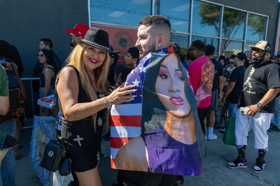 A man and woman stand smiling outside a record store.