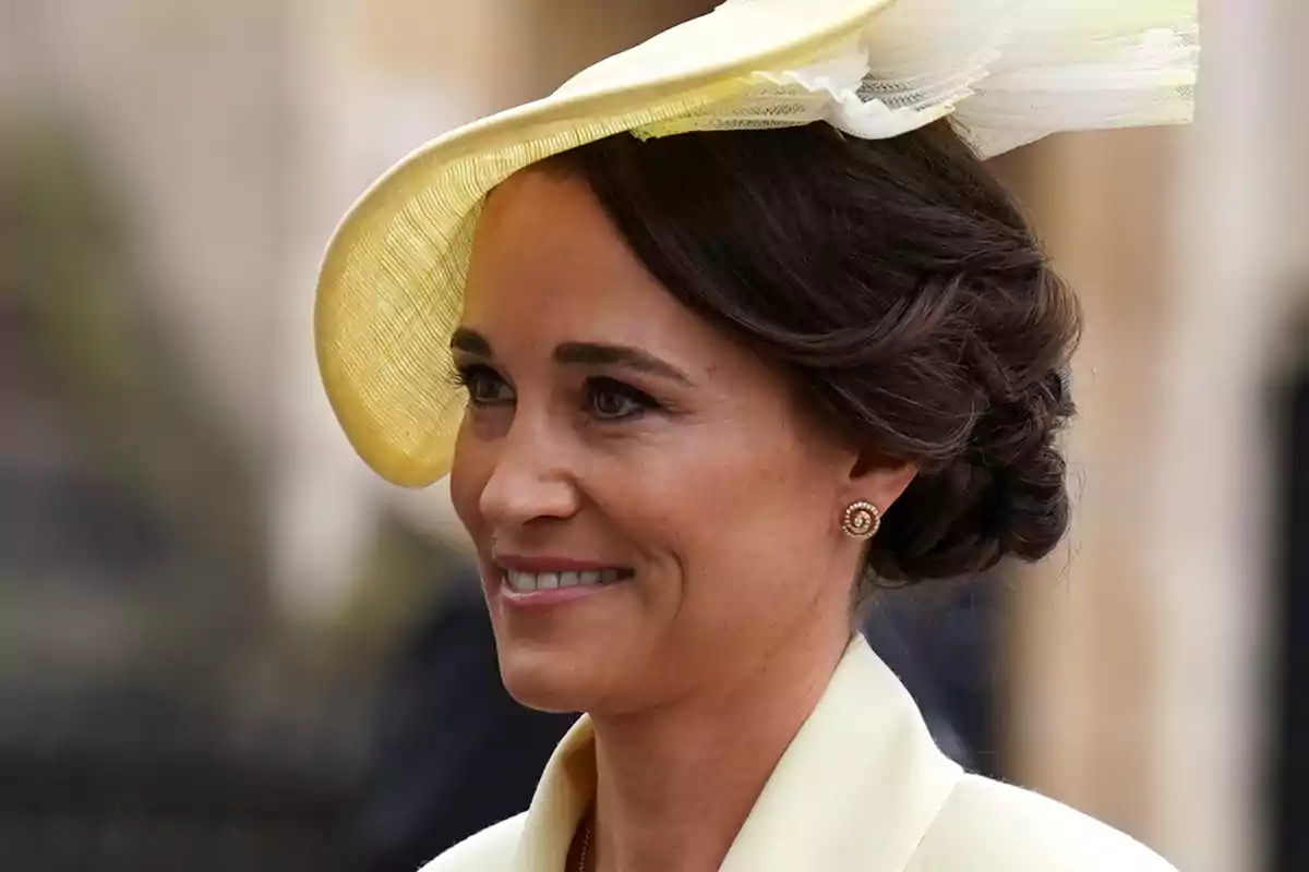Pippa Middleton in an elegant yellow hat and an updo hairstyle smiles.