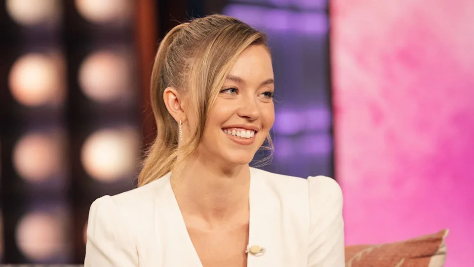 Sydney Sweeney smiles while wearing a white blazer