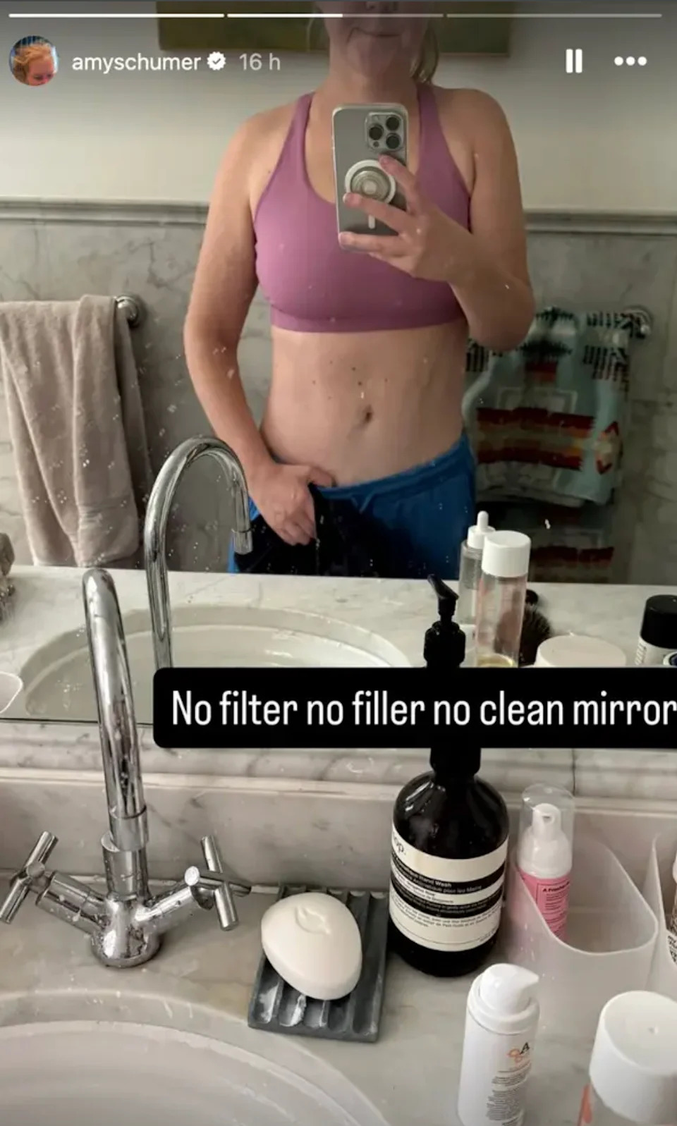 Amy wearing a sports bra and shorts taking a mirror selfie in a bathroom. Text reads "No filter no filler no clean mirror"