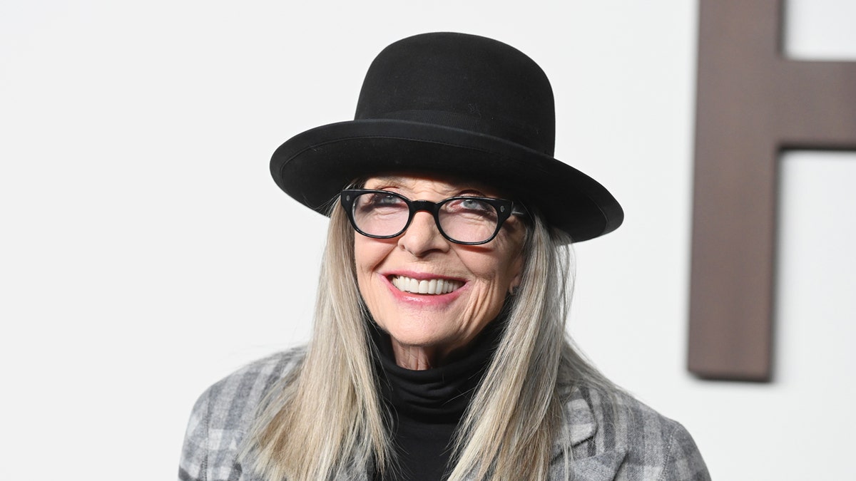 Diane Keaton wears a black hat while walking a red carpet