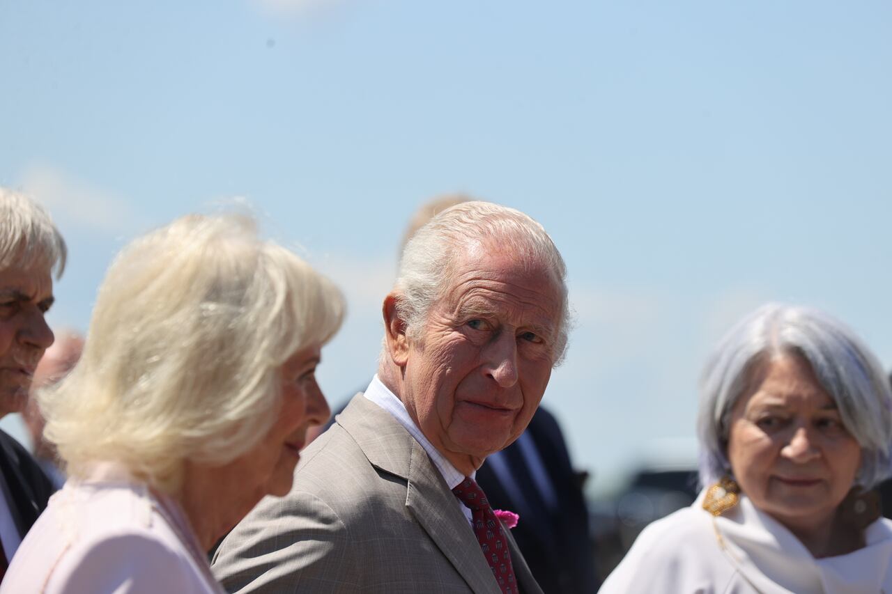 Three people are seen outside with others out of shot around them.