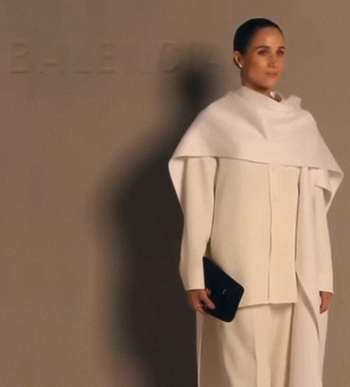 A woman in a stylish white outfit holding a black clutch, representing classier behavior after Meghan Markle backlash.