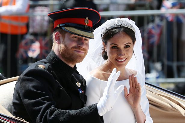 Prince Harry, Duke of Sussex and Meghan, Duchess of Sussex wave from the Ascot Landau Carriage during their carriage procession on Castle Hill outside Windsor Castle on May 19, 2018 