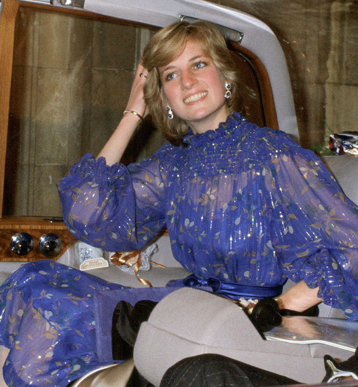 Woman in a blue floral dress smiling while sitting in a car, related to backlash over Meghan Markle's video and classier praise.