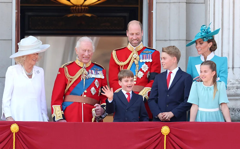 Prince Louis wears a navy suit, white shirt, and red tie at Trooping the Colour 2025