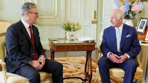 Getty Images UK Prime Minister Sir Keir Starmer meets King Charles at Buckingham Palace for the first time after winning the general election in July 2024. Both men are seated and wear dark suits, white shirt and a tie. 