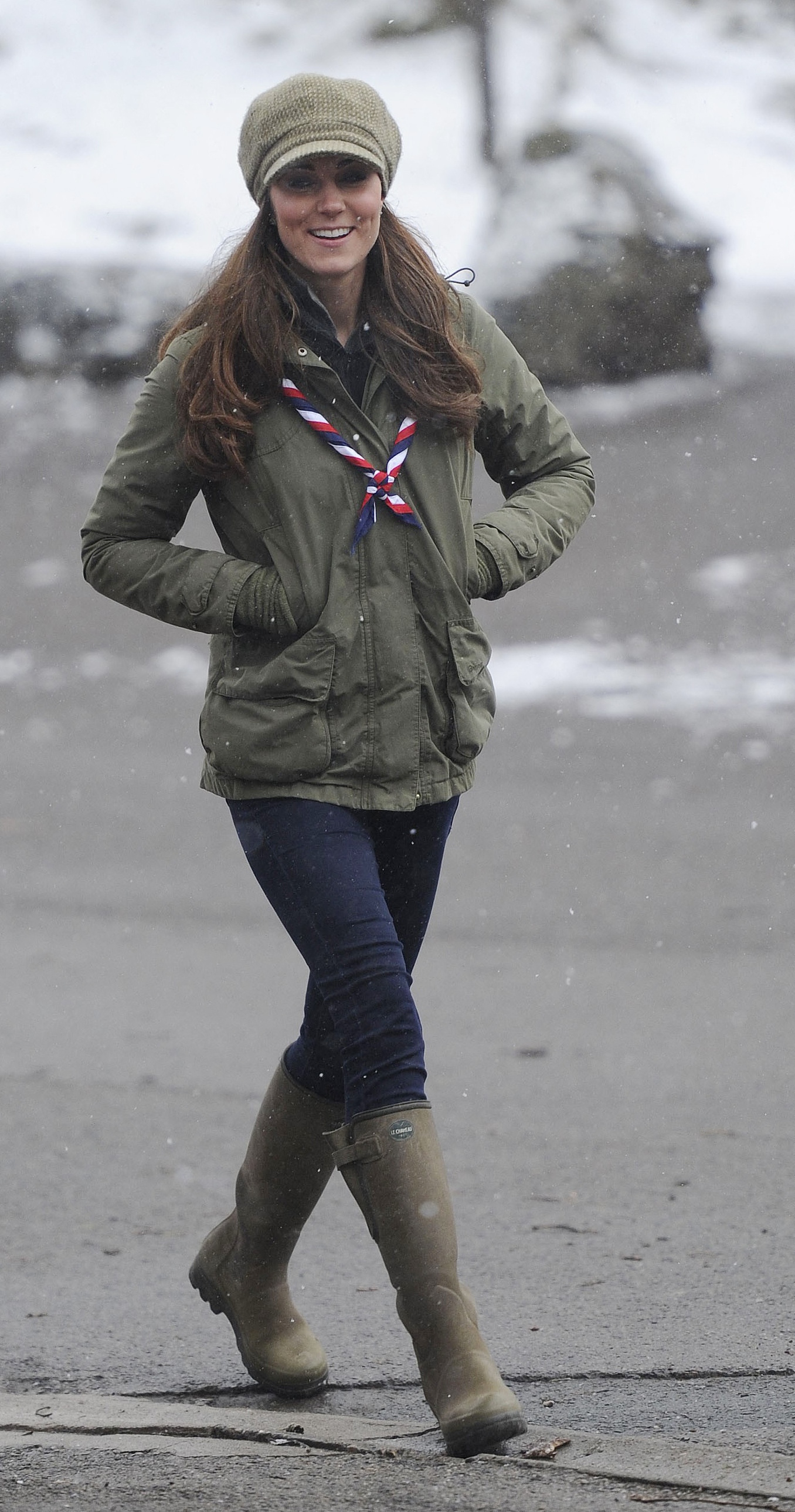 Kate Middleton wearing a green coat walking on a beach in green rain boots