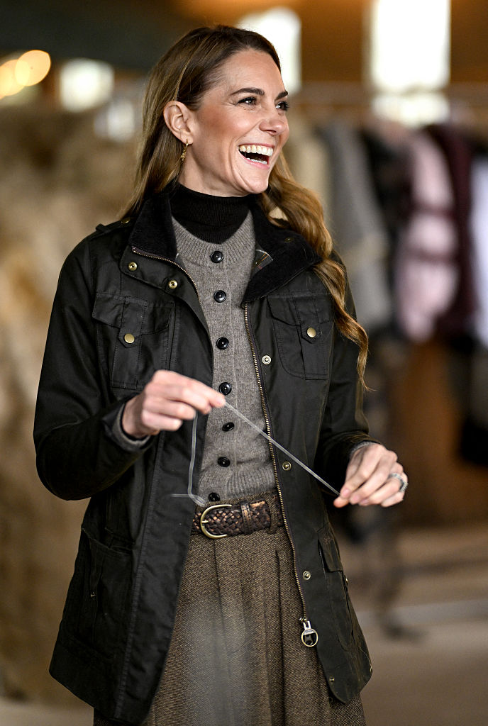 Kate Middleton wearing a cream cardigan, grey skirt and Barbour jacket.