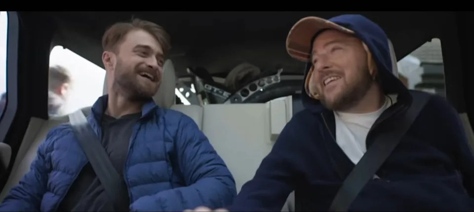 Two people sharing a joyful moment while sitting in a vehicle, both dressed casually
