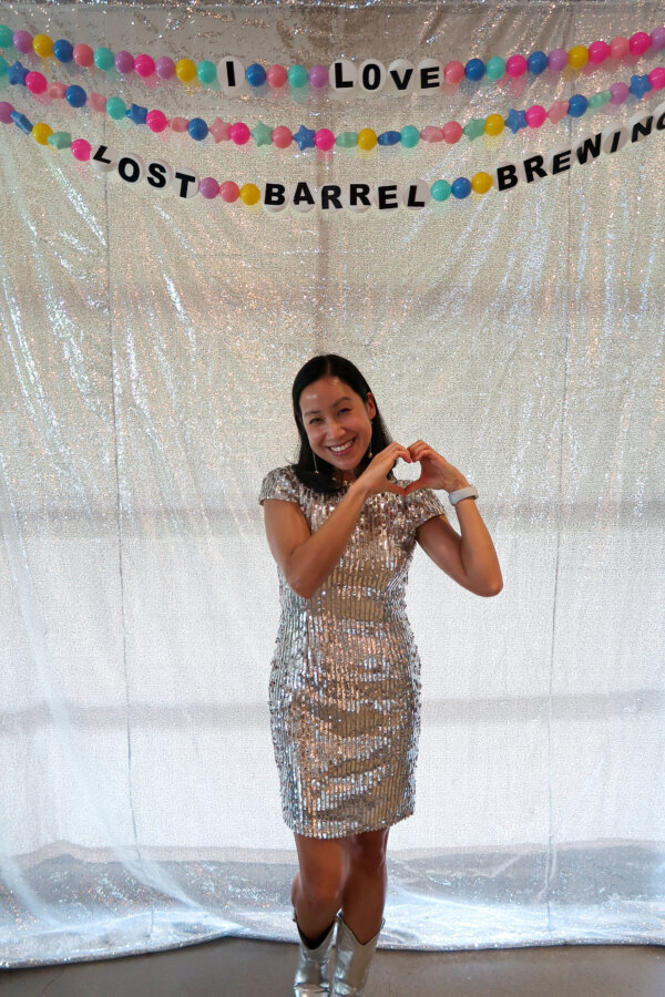 a woman holds up a heart with her hands with a friendship bracleet decoration and photobooth