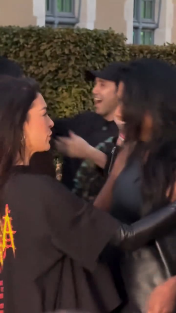 Anne Hathaway walking into the Balenciaga show at Paris Fashion Week and greeting Simone Ashley
