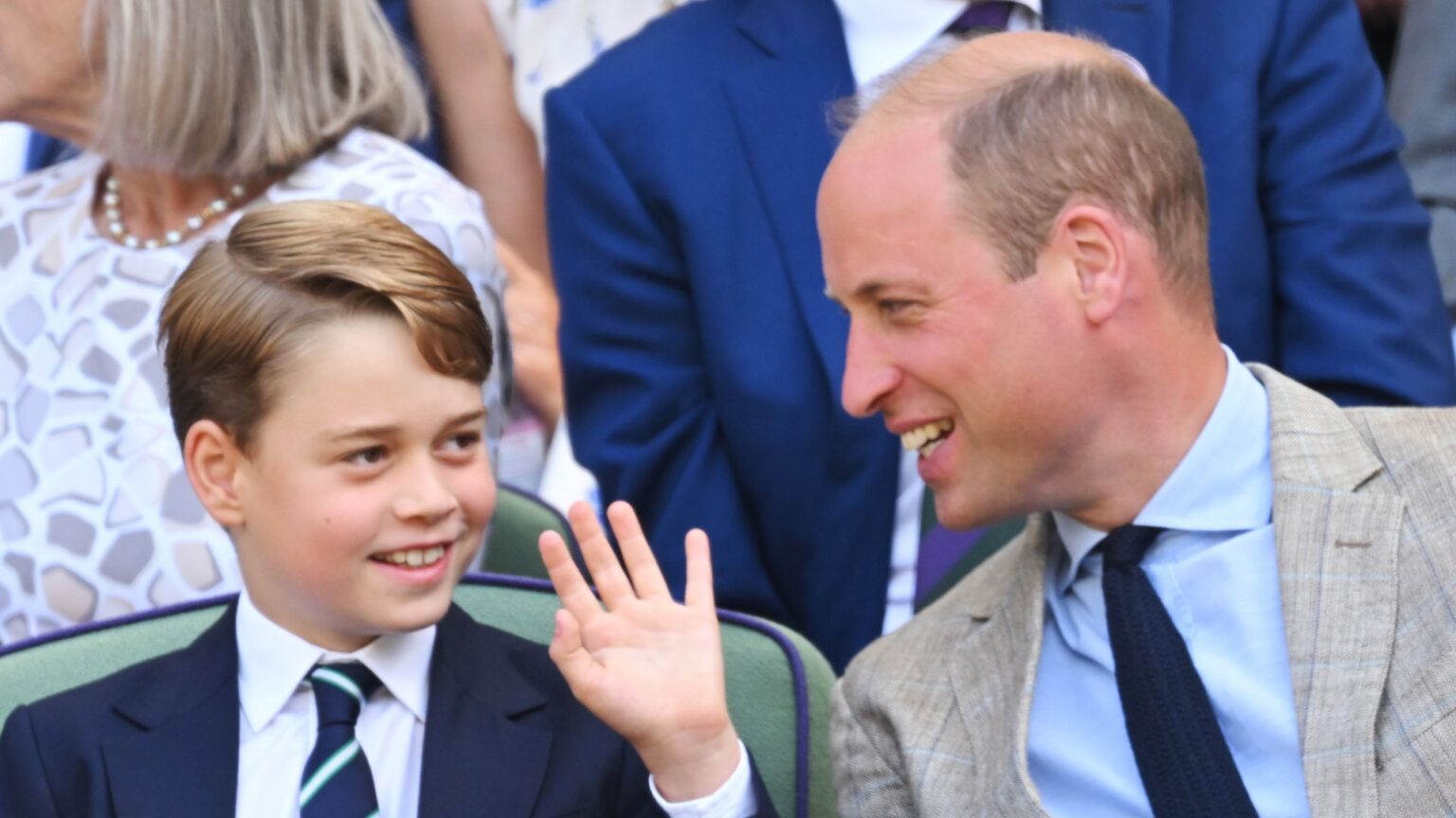 Prince George wears a blue suit and waves at the crowd as his dad Prince William laughs