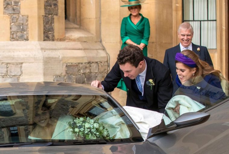 Britain's Princess Eugenie of York is helped into an Aston Martin DB10 by her sister Britain's Princess Beatrice of York (R), as she leaves with her husband Jack Brooksbank for Royal Lodge in Windsor Great Park, Windsor on October 12, 2018 after their wedding ceremony. (Photo by Steve Parsons / POOL / AFP) (Photo credit should read STEVE PARSONS/AFP via Getty Images)