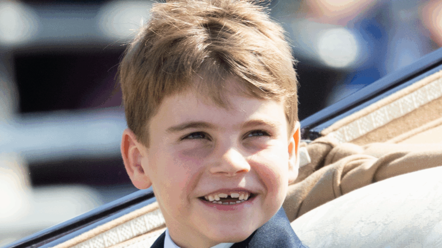 Prince Louis smiling riding in a carriage