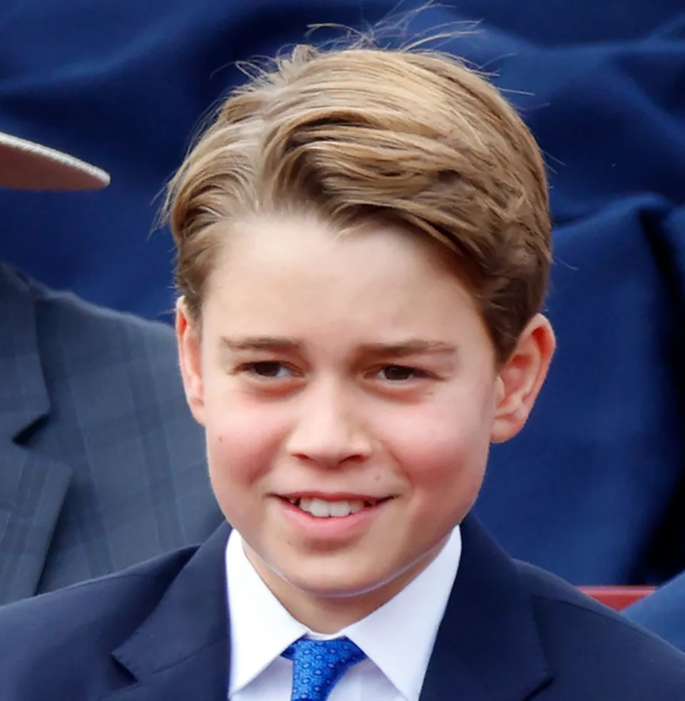 Prince George wearing a blue suit and smiling.