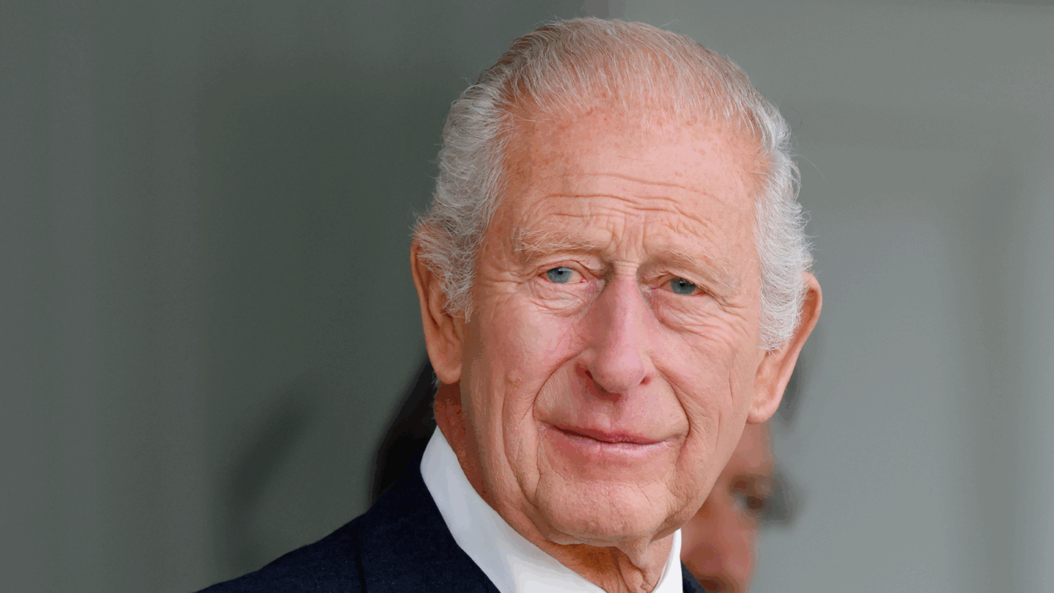 A headshot of King Charles wearing a suit and tie