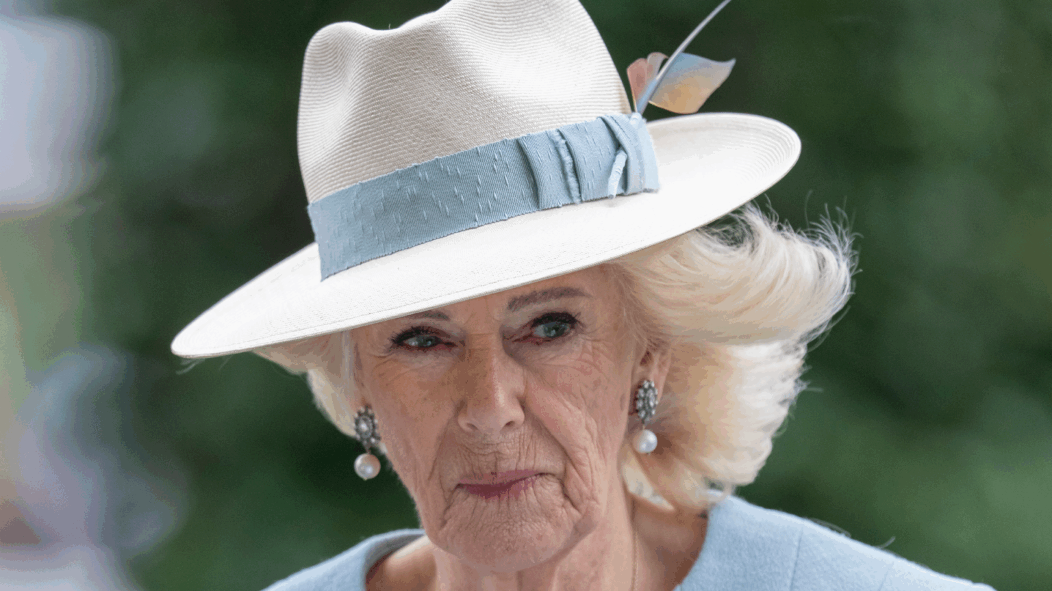 Queen Camilla wearing a fedora with a blue band and pale blue coat