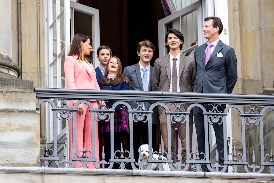 Princess Marie, Prince Joachim and their four kids and dog standing on a palace balcony